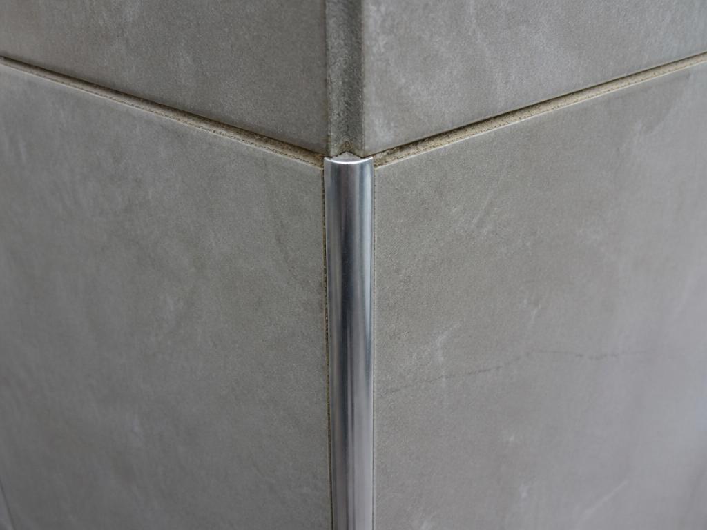 Tiled corner finished with a visible metal trim strip